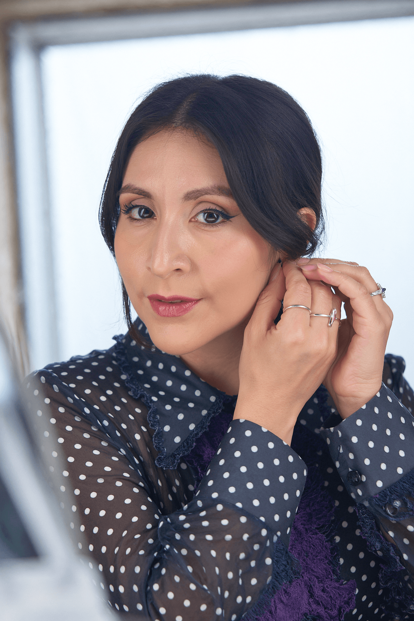 Vane con traje celeste junto a un perchero de prendas